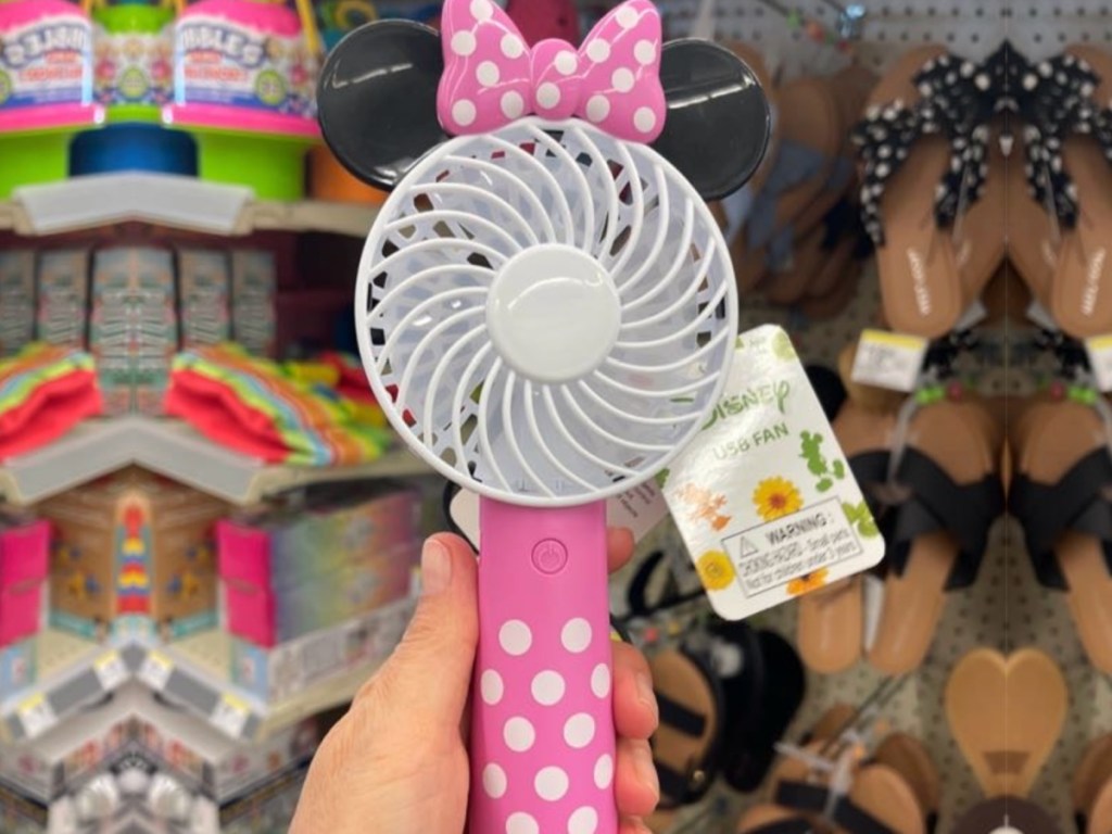 Woman holding up Minnie mouse fan inside Walgreens store featuring white polkadots