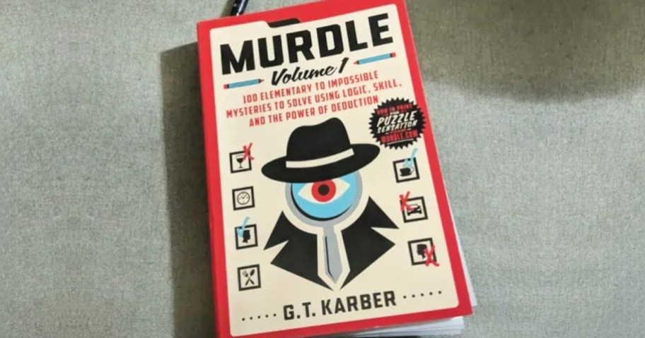Murdle Volume 1 on a neutral upholstered chair