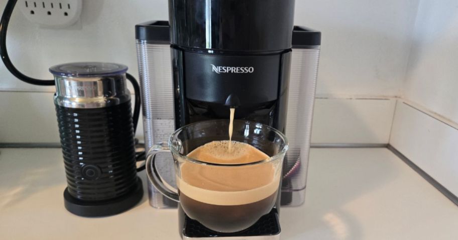 Nespresso Evoluo Coffee & Espresso Maker on counter brewing espresso into clear coffee cup