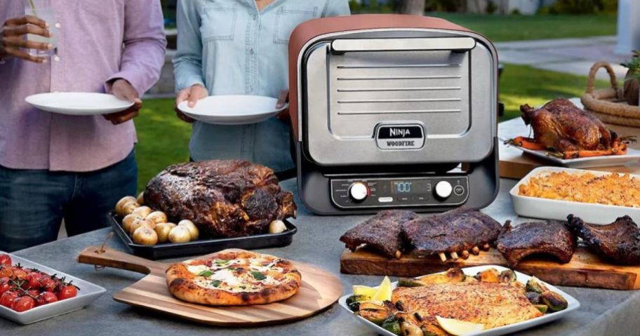 Ninja Woodfire Pizza oven surrounded by plates of food you can make in it