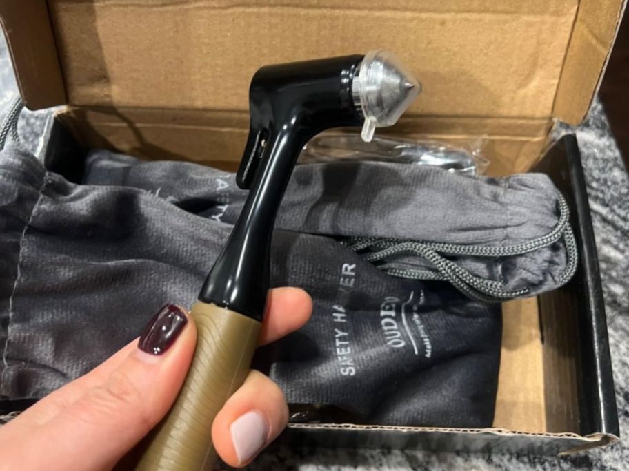 A woman holding a car window breaker that looks like a small hammer