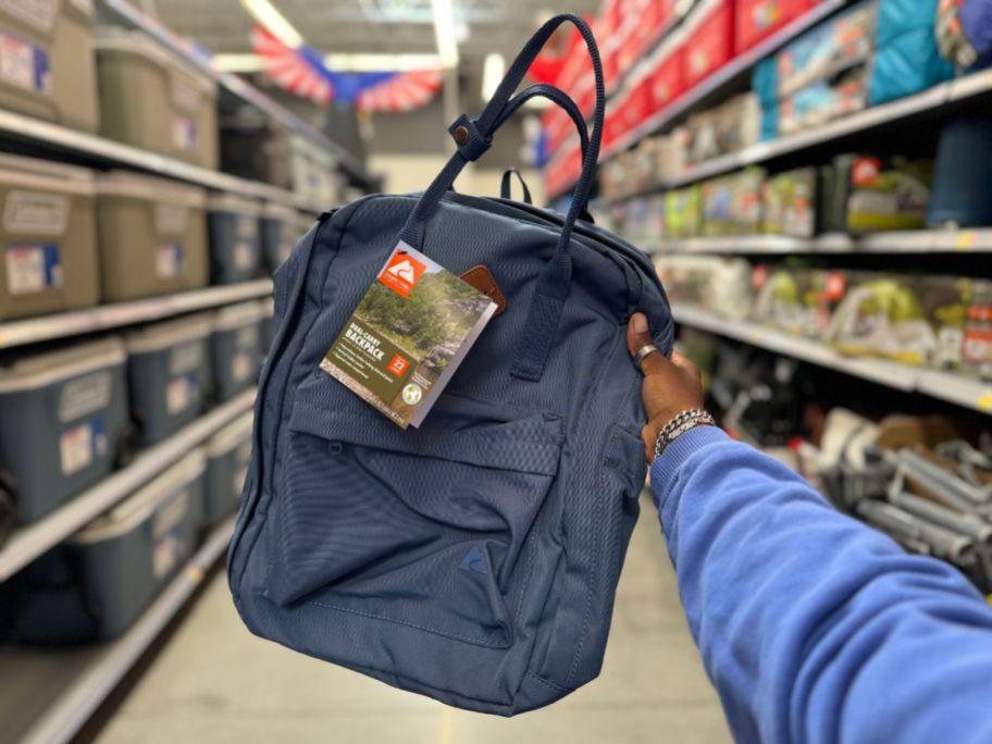 A person holding a blue backpack in a store