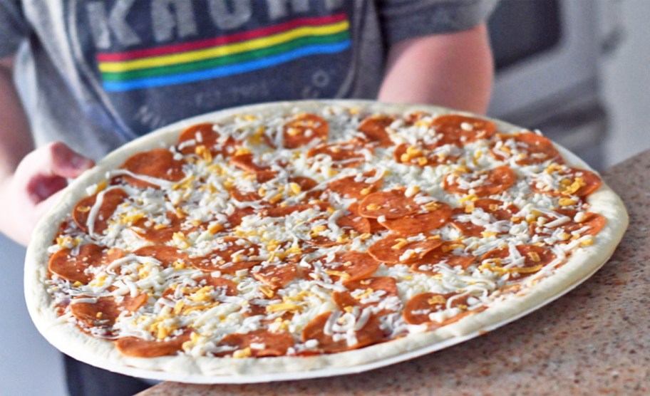 boy holding an uncooked pepperoni Papa Murphy’s Pizza