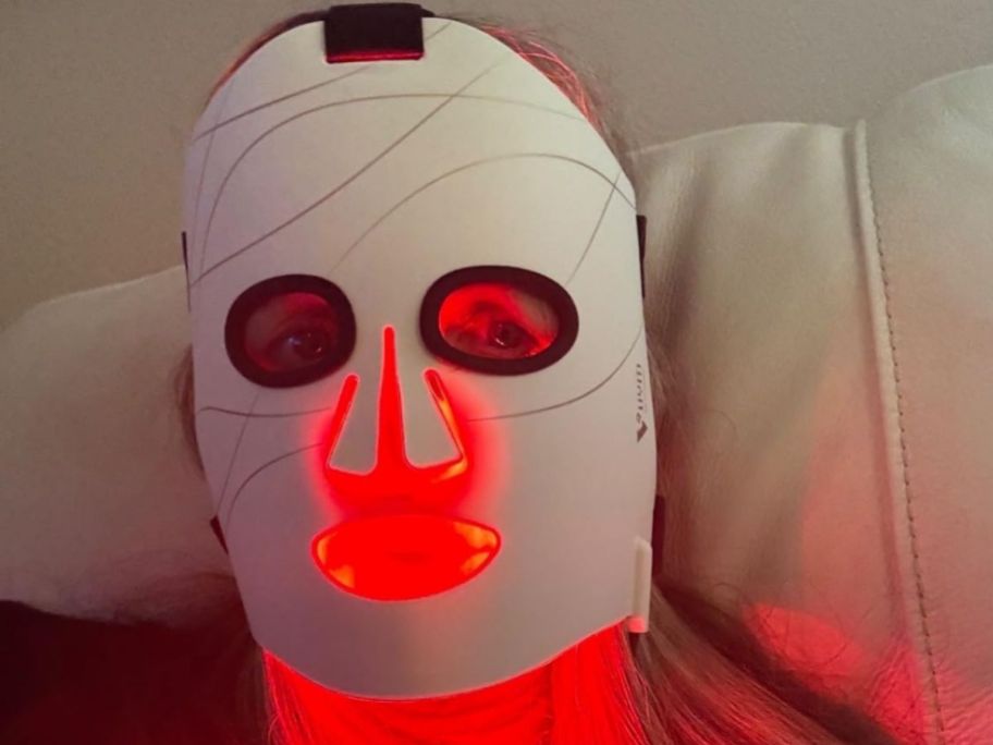 woman wearing a red light therapy mask while laying down