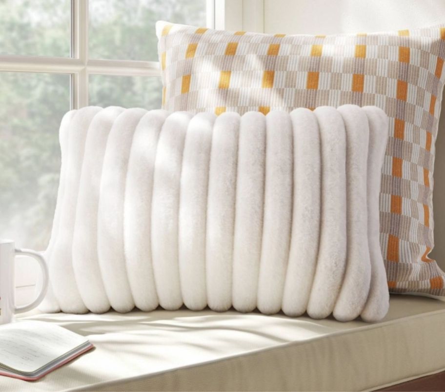 a white channeled faux fur pillow on window seat