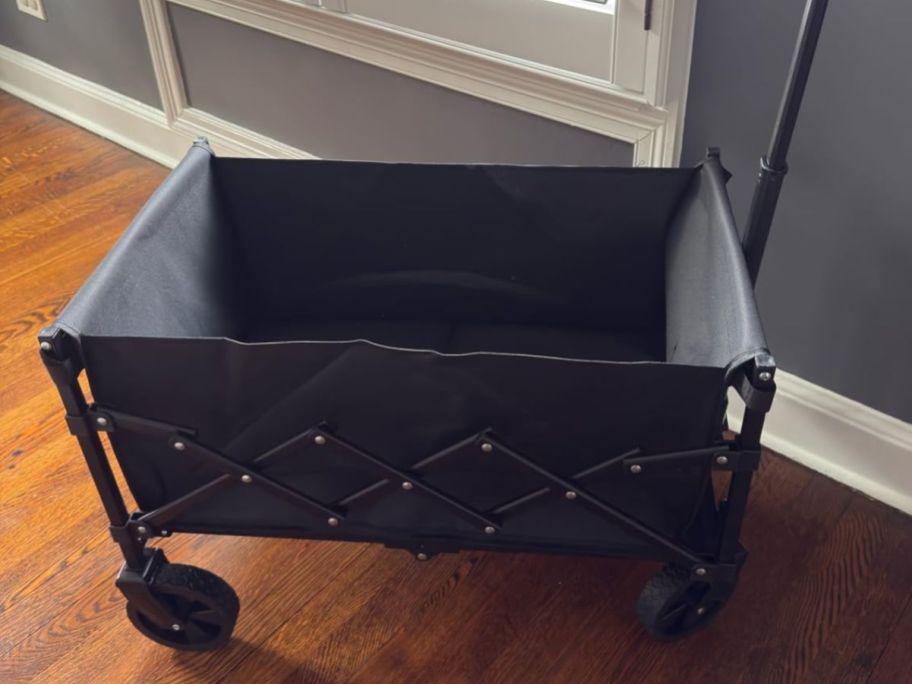 A collapsible fabric wagon in black inside a home