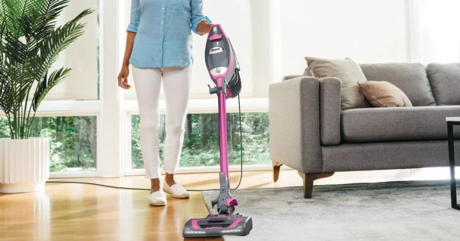 Woman using a pink Shark Rocket Pro DLX Corded Stick Vacuum