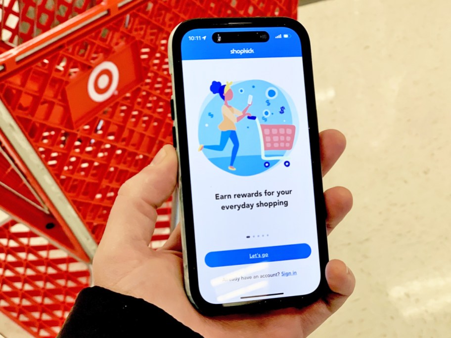 hand holding a phone displaying shopkick app in front of red target shopping cart