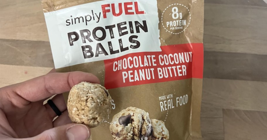 SimpleFuel Protein Balls bag on a counter with a hand holding one protein ball
