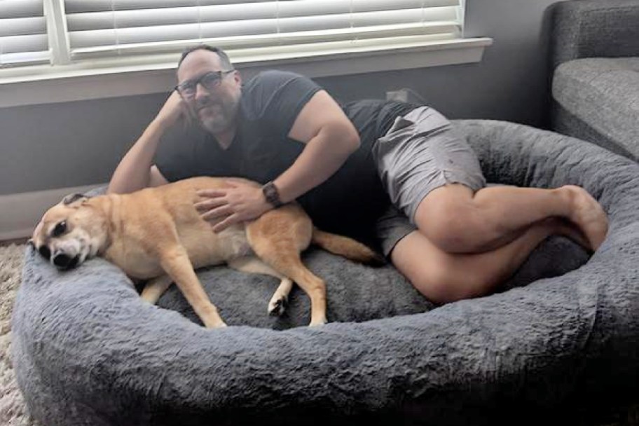 a man and dog in a large dog bed