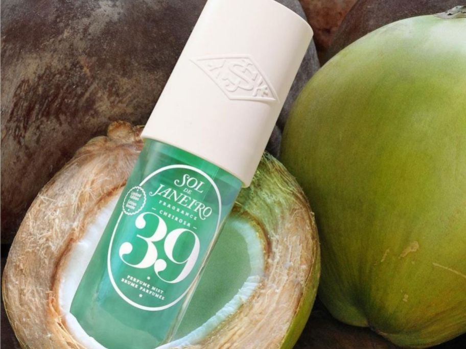 Sol de Janeiro 39 spray inside of a coconut next to a green coconut
