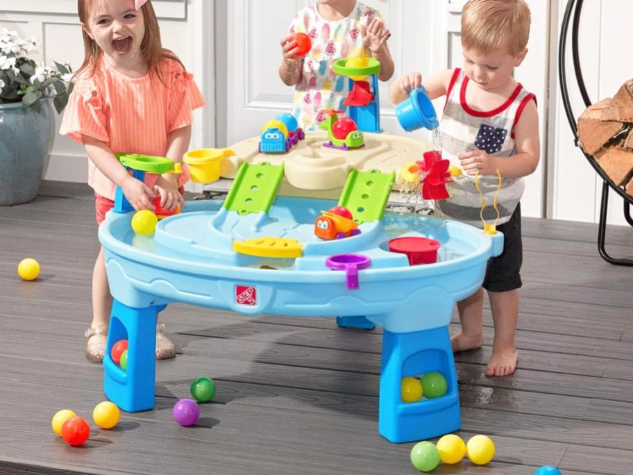 three kids playing with a blue water table on deck