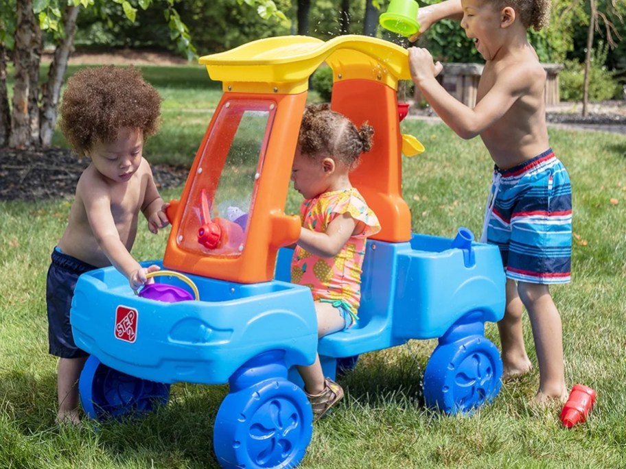three kids playing with a colorful car-shaped water table
