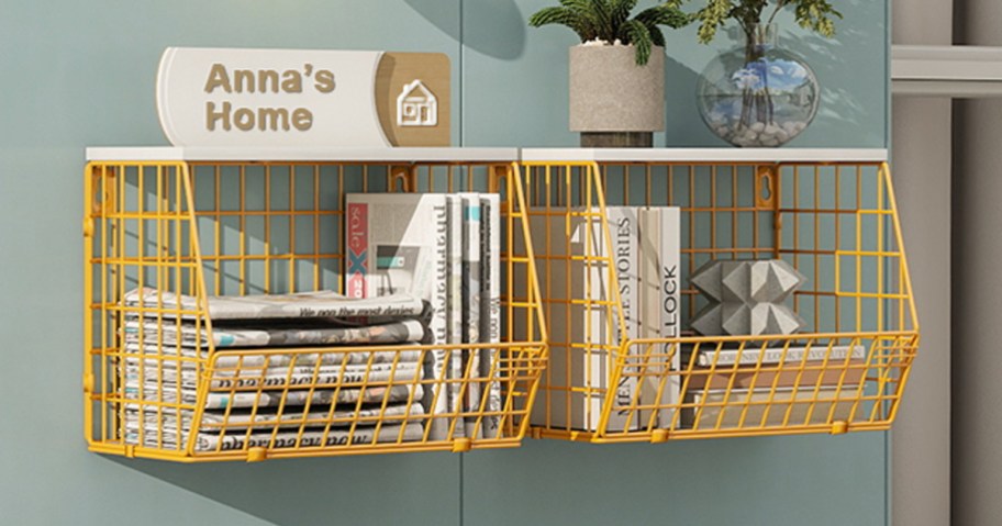 two storage baskets mounted on a wall with books and other supplies inside them