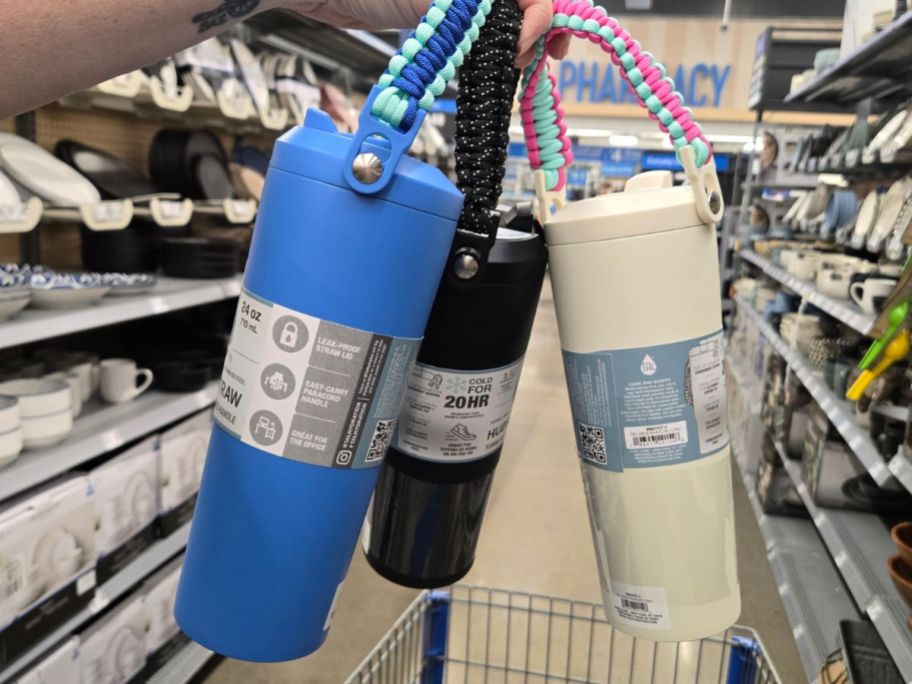 A woman holding 3 water bottles 