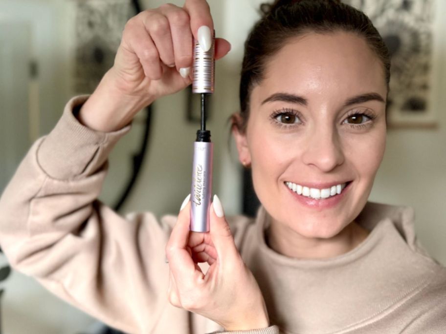 Woman holding tarte mascara up to her face showing the volume in her lashes