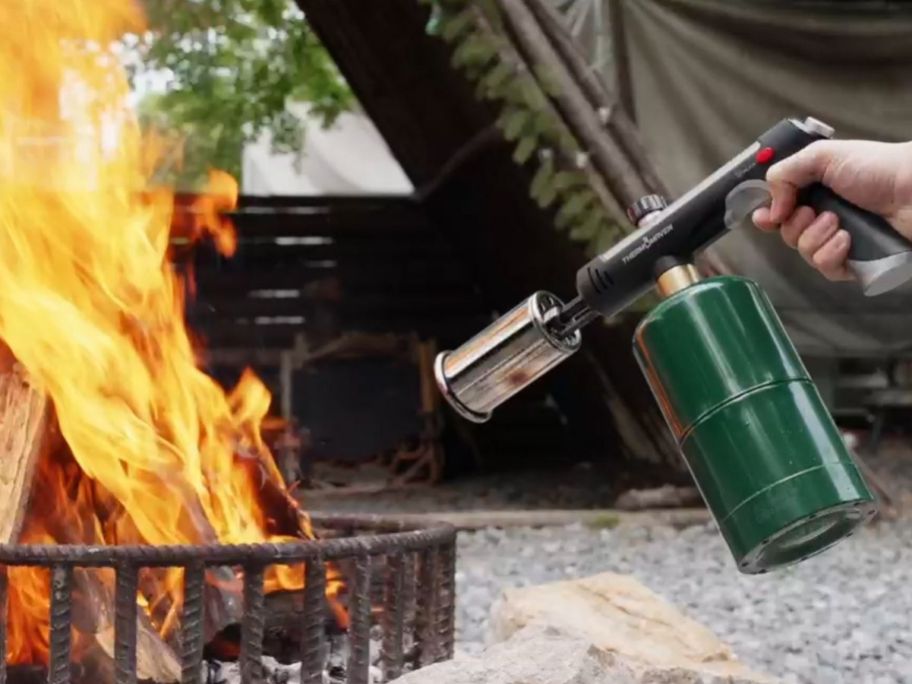 hand holding propane touch lighting a firepit