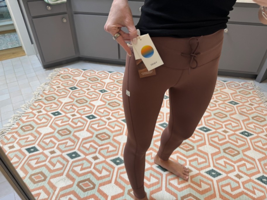 woman wearing brown vuori leggings with tag attached