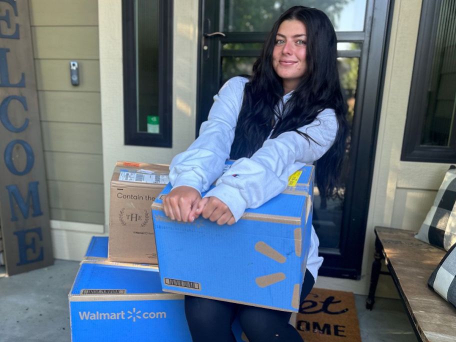 Teen girl holding Walmart shipping boxes while sitting on a porch