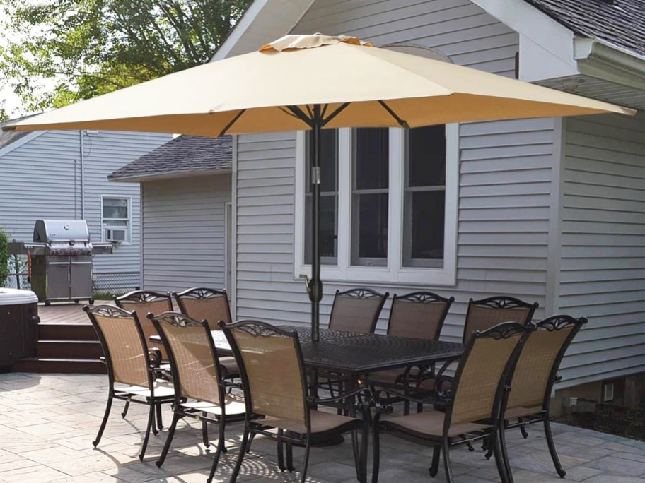 tan rectangular patio umbrella over a dining set in backyard