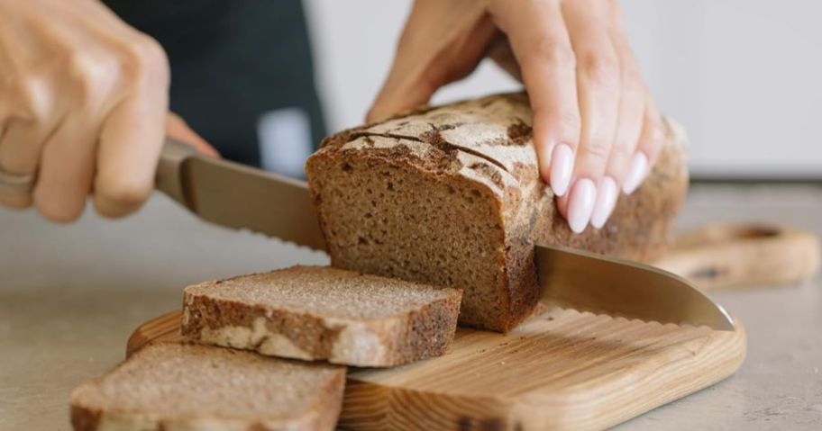 A person cutting a loaf of bread with a Zulay Serrated Bread Knife 