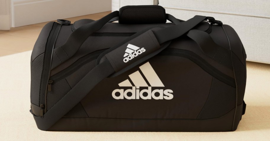 black and white adidas duffle bag on floor