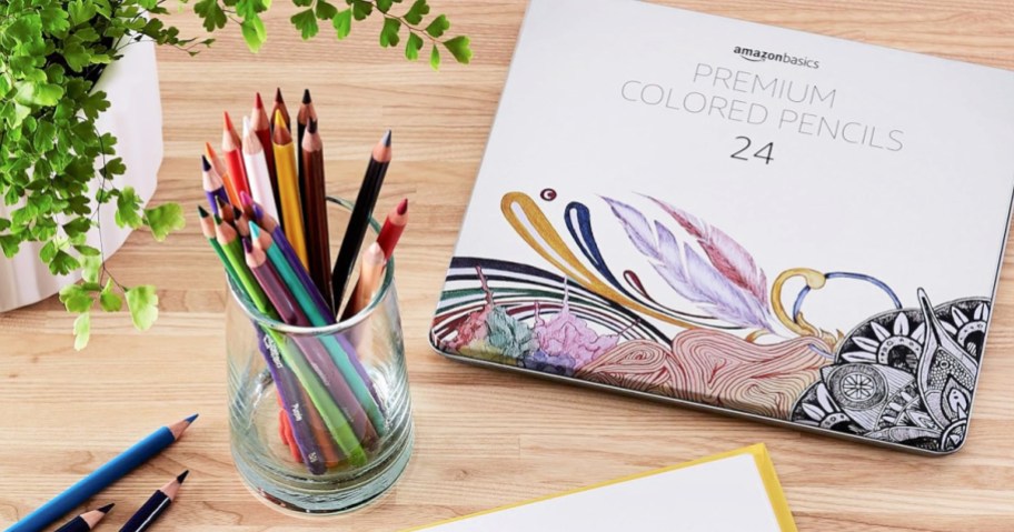 colored pencils in a glass next to their tin