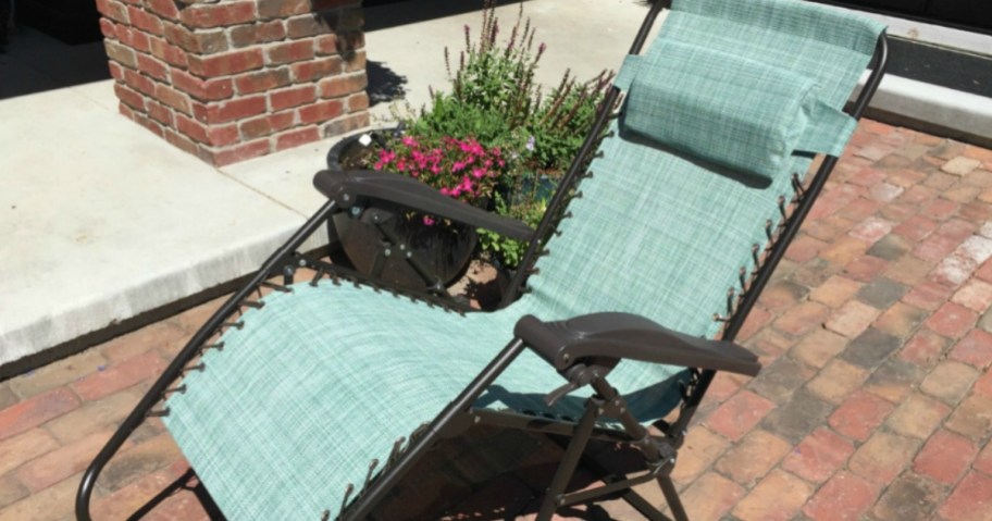 teal zero gravity chair on a brick patio