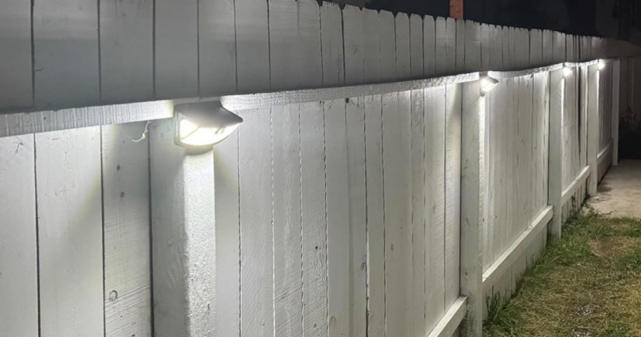 solar lights hanging on a white wooden fence