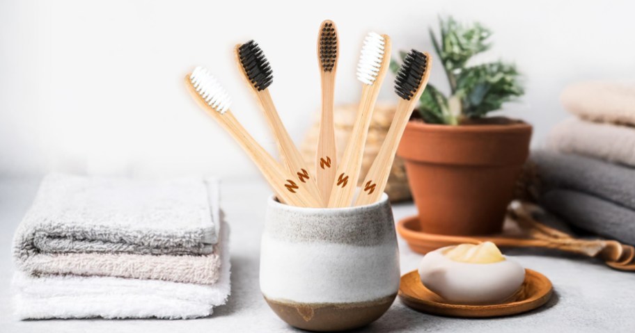 bamboo toothbrushes on a counter in a cup 