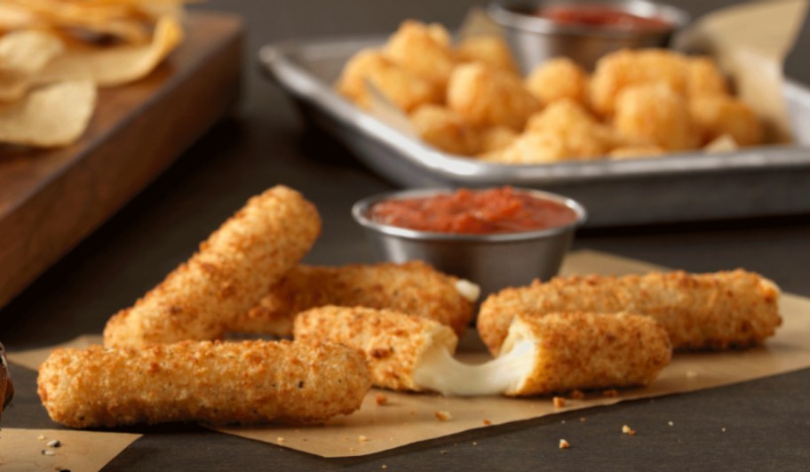 mozzarella sticks on a wrapper next to marina sauce
