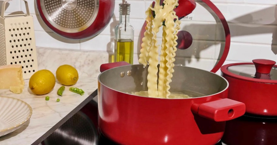 red pot with pasta cooking inside on stove 