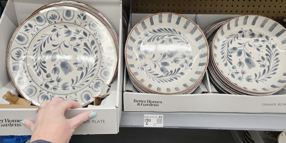 hand reaching for dinner plate and bowls on shelf in store
