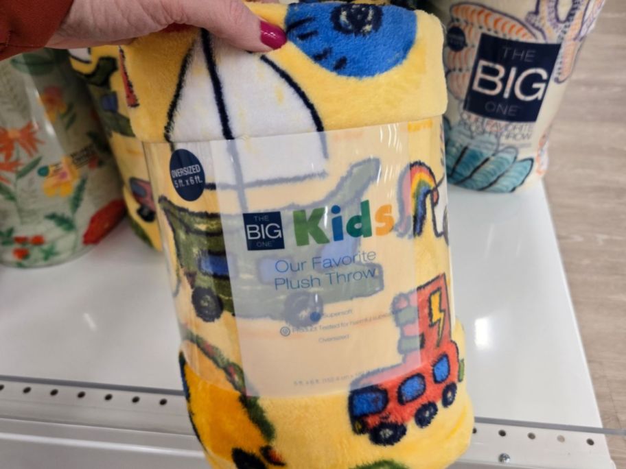 hand holding yellow big one blanket with cars and boats on it