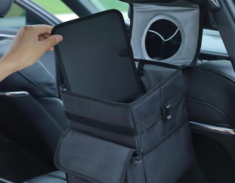 person showing car trash can mat in back of car