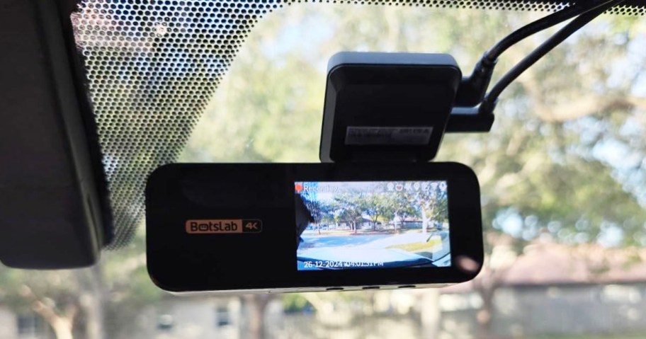 black dash cam with hanging on car window with video image on it 