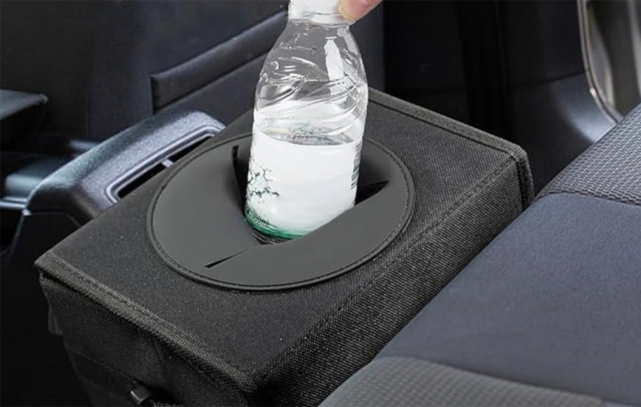 hand putting a water bottle in to car trash can