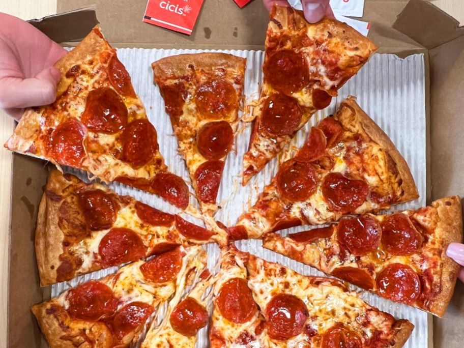 a pepperoni pizza with several hands grabbing a piece