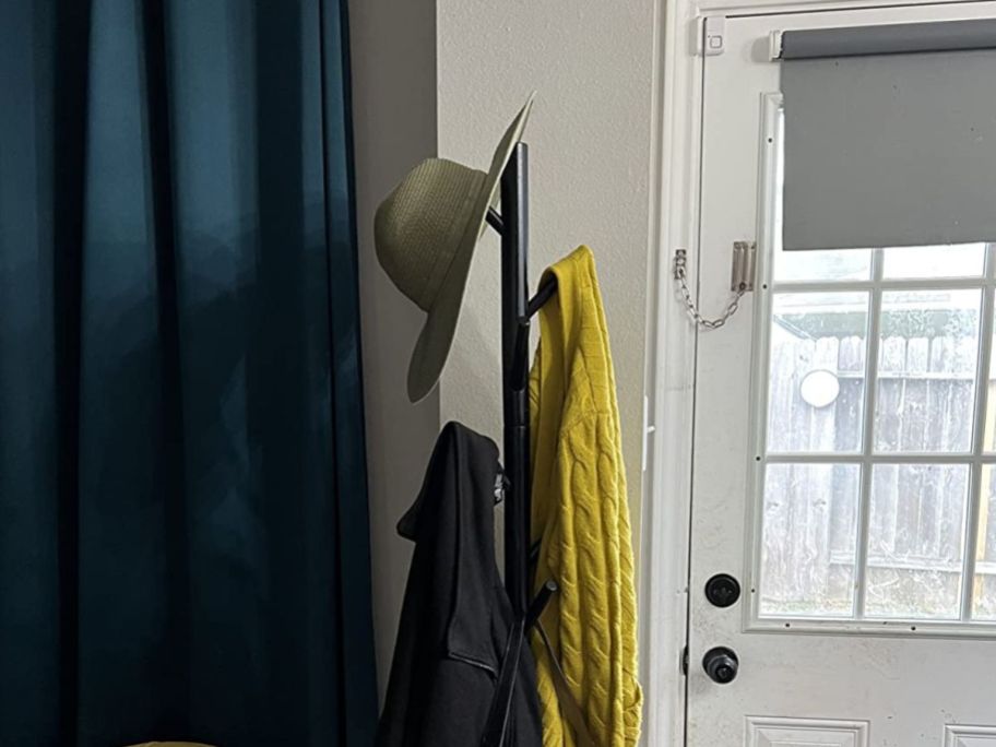 hat, sweater, and coat hanging on coat rack near door