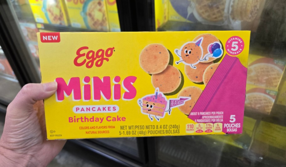 hand holding birthday cake mini pancakes box in front of freezer