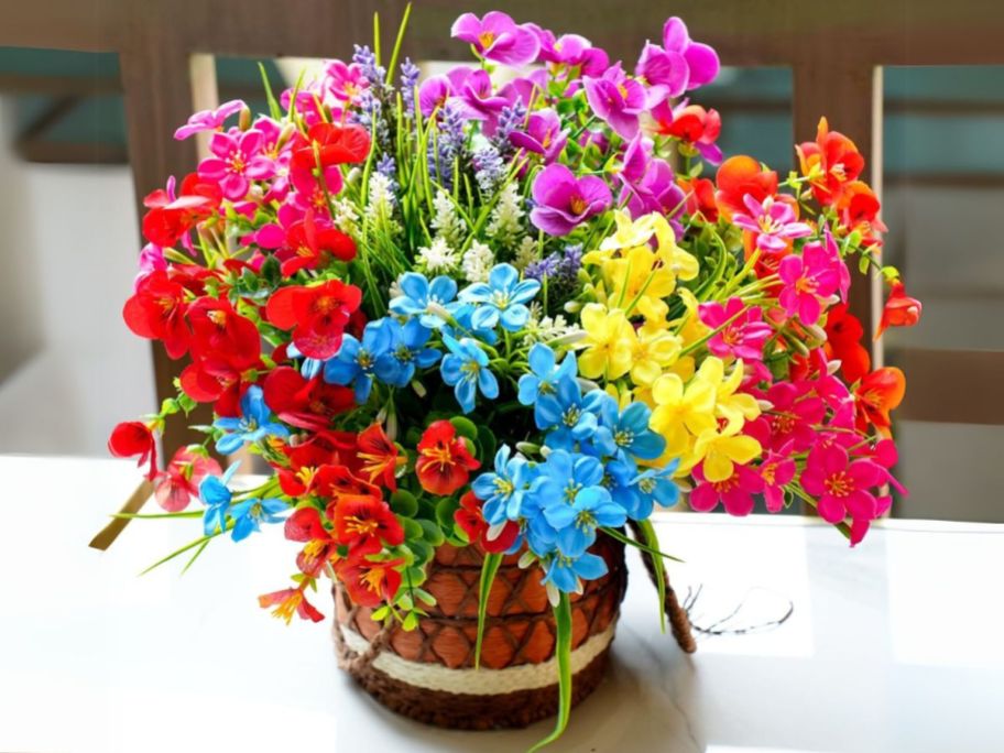 red, blue, pink, and yellow artificial flowers in pot on table