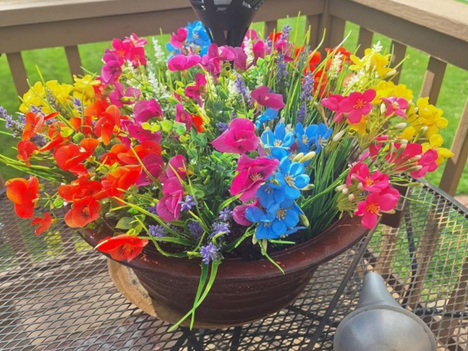 red, blue, pink, and yellow artificial flowers in pot on porch