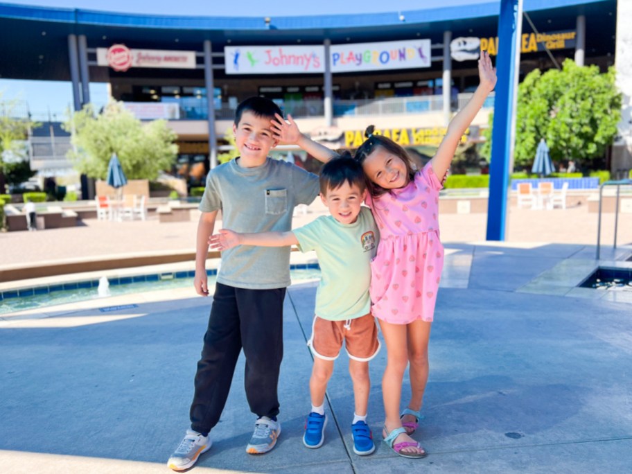 three kids standing under canopy looking excited