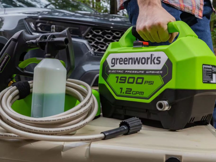 man grabbing Greenworks 1900 PSI 1.2 GPM Electric Pressure Washer by handle