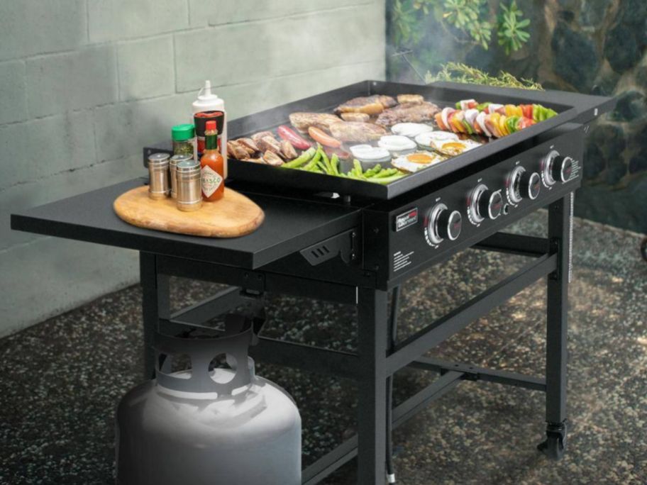 Royal Gourmet 35" 4-Burner Propane Gas Grill Griddle in yard with food being cooked on it