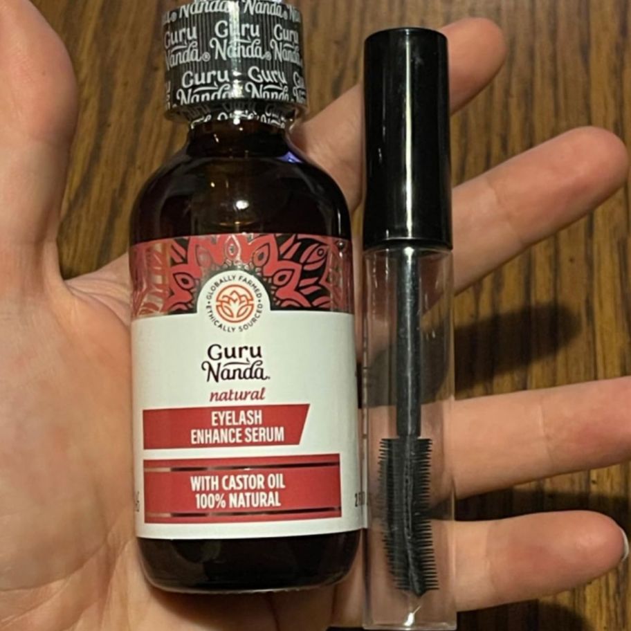 a womans hand holding a bottle of eyelash serum and a vial with lash applicator