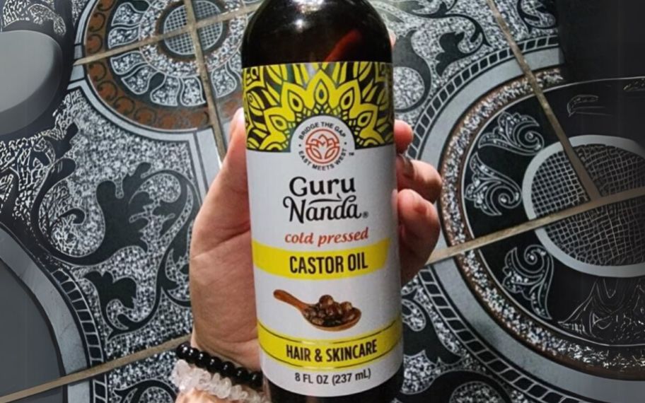 a womans hand holding a bottle of castor oil