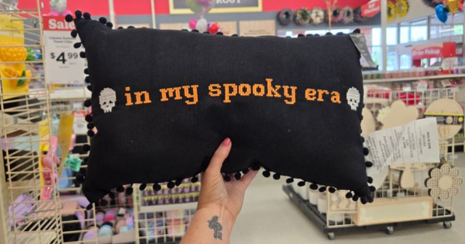 hand holding black pillow with in my spooky era on it in store