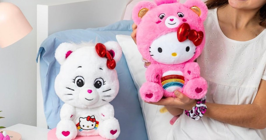 child holding pink care bear with white care bear plush toy on table
