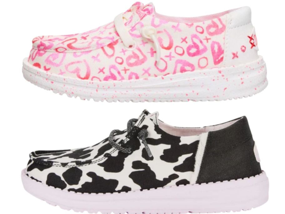 two pair of kids slip on shoes, one in a pink and black cow print and the other in a white and pink heart print